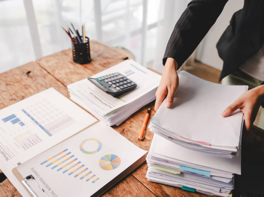 Small business owner reviewing financial documents with a calculator while managing company accounts